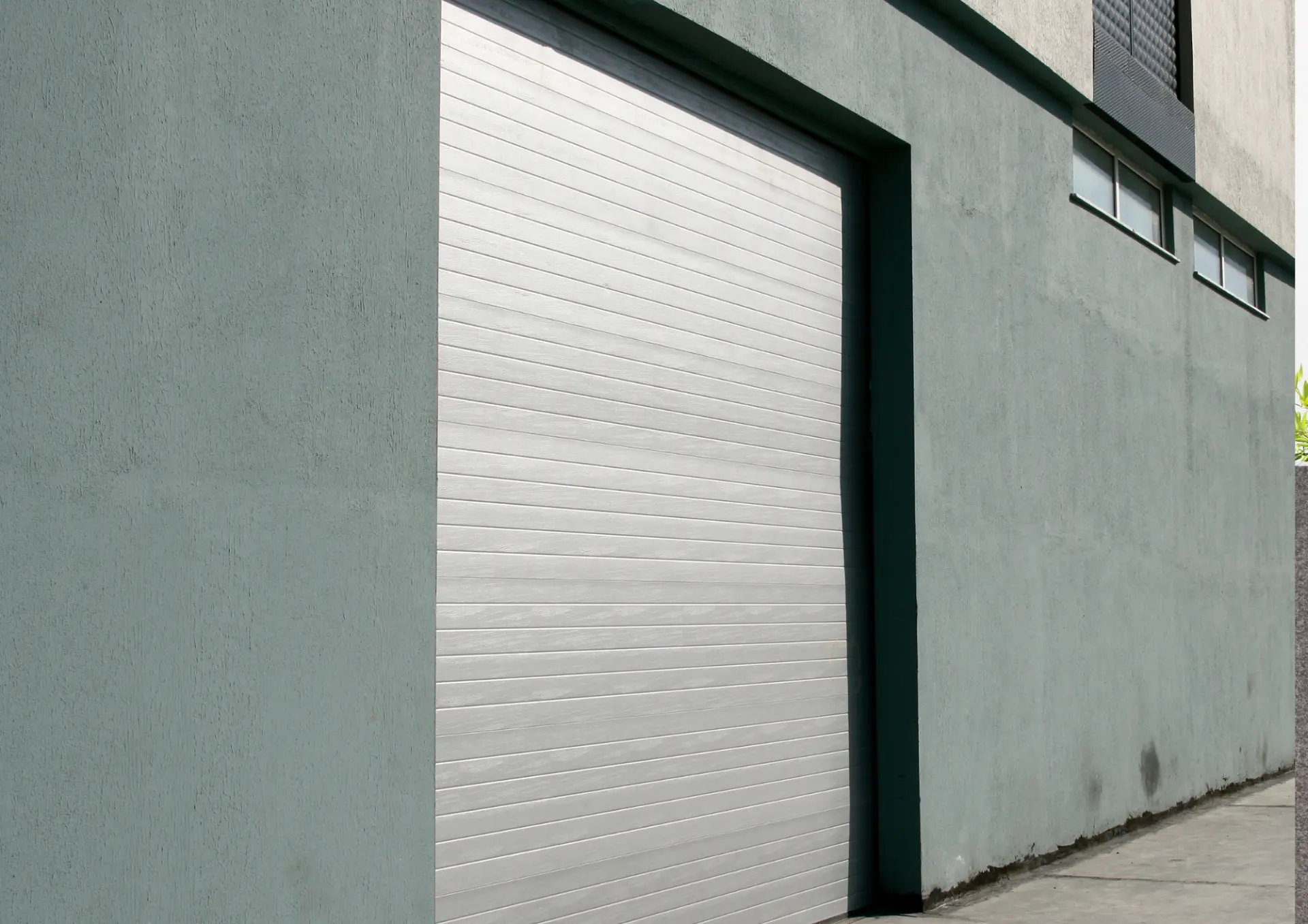 Porte de garage enroulable grise fermée sur un local professionnel