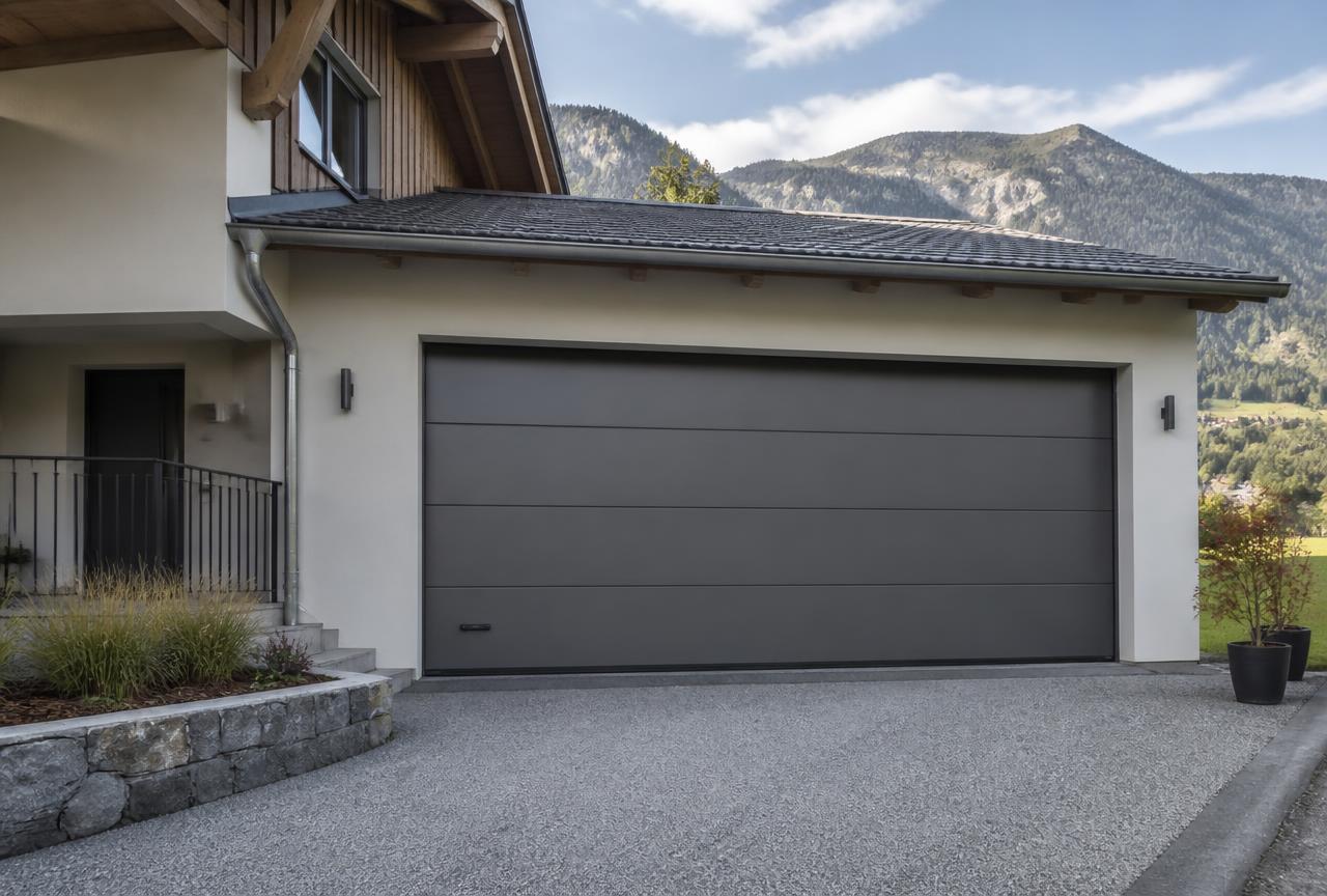Porte de garage sectionnelle grise installée sur une maison alpine